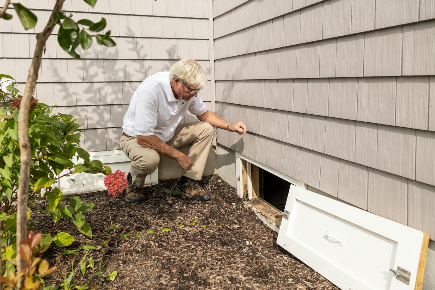 A home inspector examining the crawl space access door of a Charlotte-area home